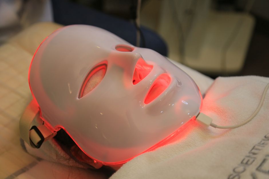 LED light therapy mask glowing red, worn during a treatment session