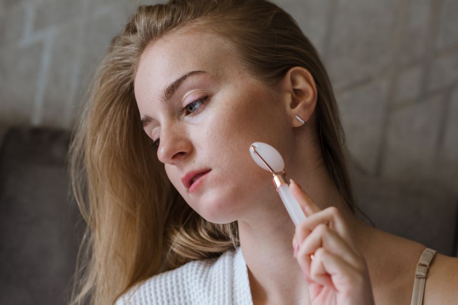 Slim red light skincare wand gliding across the cheek